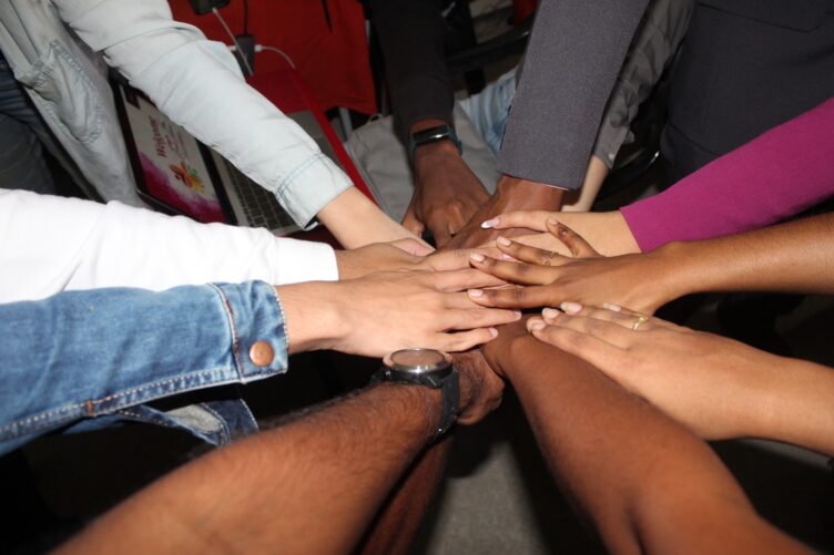 arms all reaching in with hands covering each other in a "huddle"